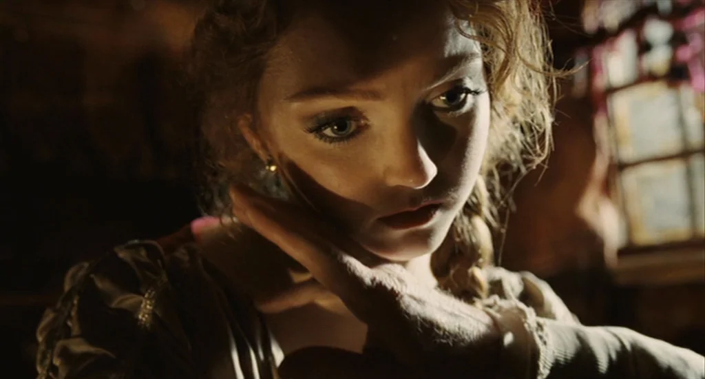 The Imaginarium of Doctor Parnassus (2009) movie still: closeup — A dimly lit interior space with a small window casting light on a woman. She holds…