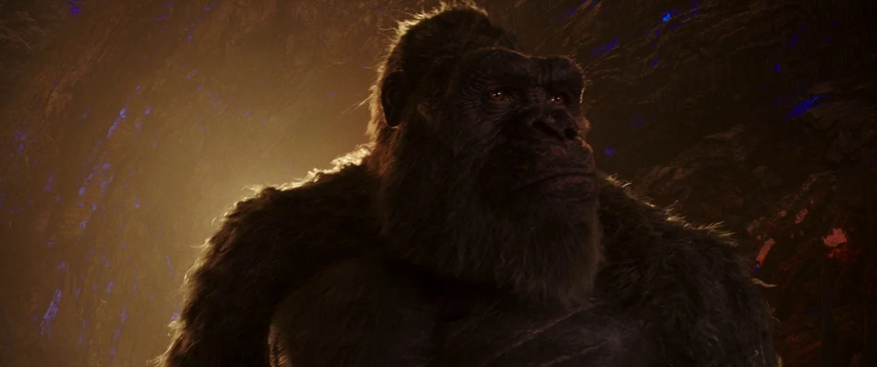 Godzilla Vs. Kong (2021) movie still: medium — A giant gorilla stands inside a dark, rocky subterranean cavern with jagged stone walls.…