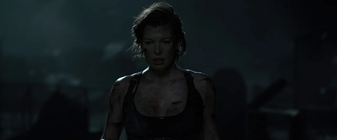 Resident Evil: The Final Chapter (2016) movie still: medium — A dark, rubble-filled exterior environment obscured by deep shadow. A woman with short…