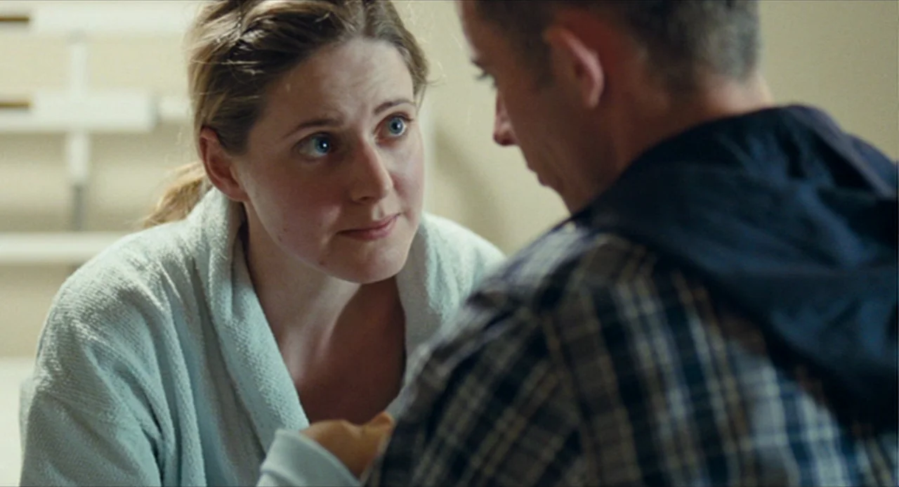 The Angel’s Share (2012) movie still: medium — A hospital room with pale walls and medical equipment visible in the background. A woman watches a…