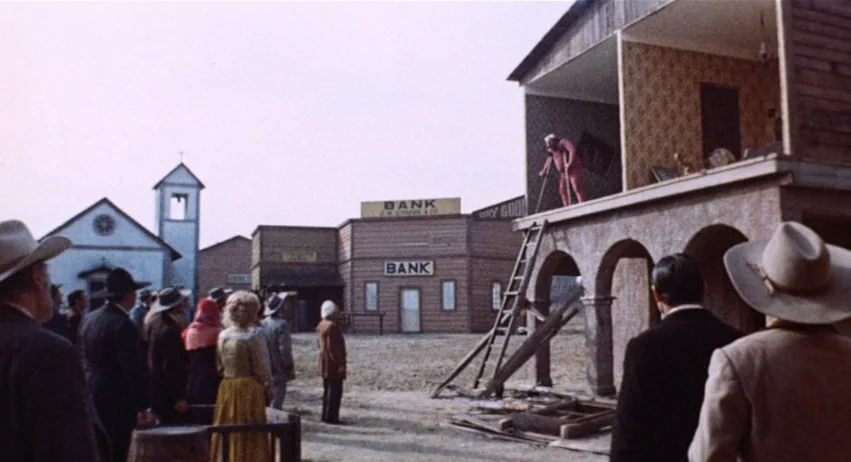 Roy Colt and Winchester Jack (1970) movie still: wide — A sparsely populated Old West town set features wooden buildings and a church spire. A man…