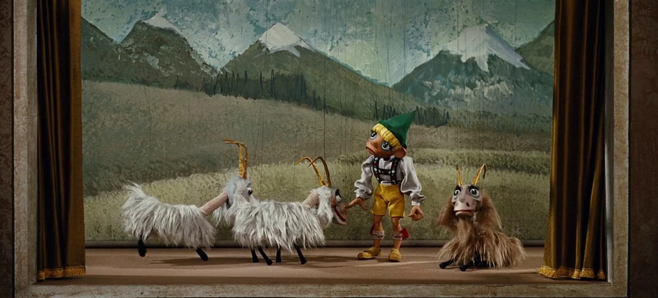 The Sound of Music (1965) movie still: fullbody — A miniature puppet theater stage features a painted alpine backdrop with snow-capped mountains. A…