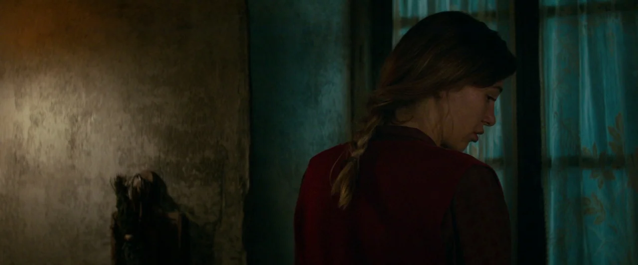 Overlord (2018) movie still: medium — A dimly lit, rustic room features a textured wall and a curtained window. A young woman with a braided…