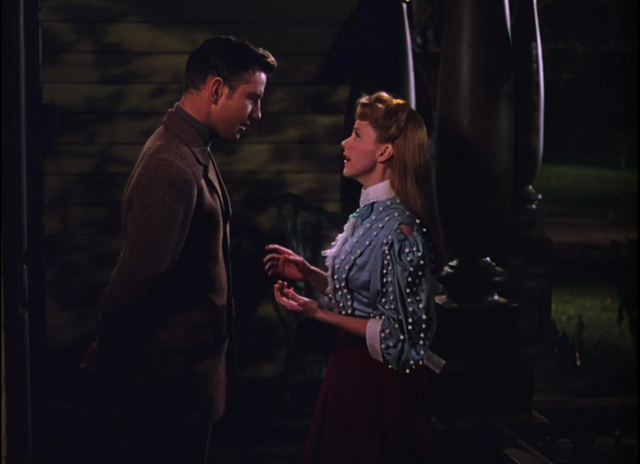 Meet Me In St. Louis (1944) movie still: medium — A dark, residential porch exterior features wooden siding and large structural columns at night. A…
