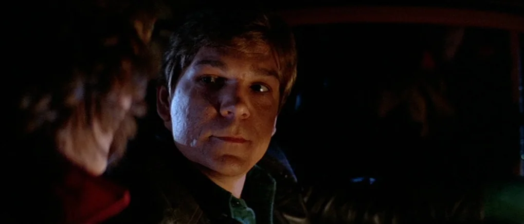 The Fog (1980) movie still: closeup — The interior of a dark vehicle at night with two people inside. The man in the driver's seat turns to look at…