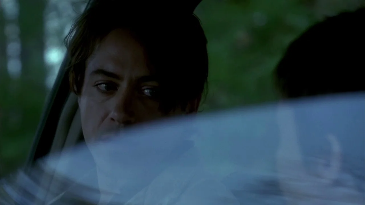 In Dreams (1999) movie still: closeup — Interior of a car with a view of greenery through the side window. A young man sits in the driver seat…