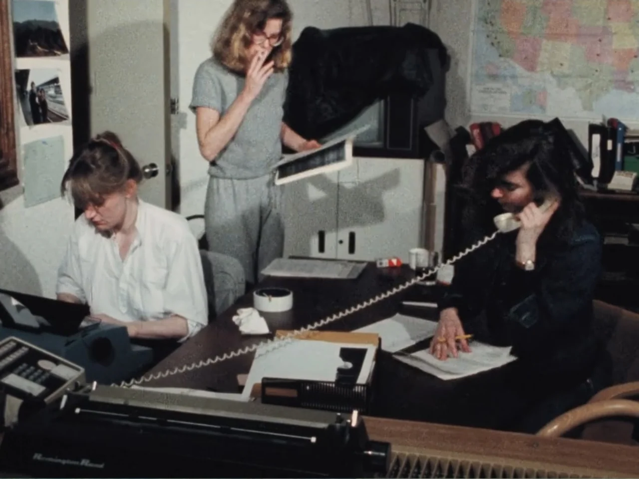 Born in Flames (1983) movie still: medium — An office environment contains desks equipped with typewriters, telephones, and paperwork. Three women…