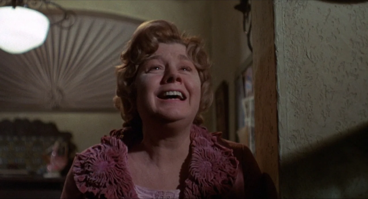 What’s the Matter with Helen? (1971) movie still: medium — A dimly lit indoor space features textured plaster walls and a visible overhead lamp. A…