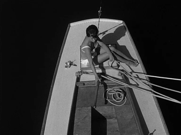Knife In The Water (1962) movie still: fullbody — A wooden sailboat deck is illuminated at night against a pitch black surrounding surface. A woman…