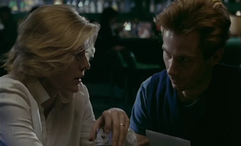 No End (1985) movie still: medium — A dimly lit diner booth interior at night with dark green seating. A woman and a man sit across from each other…