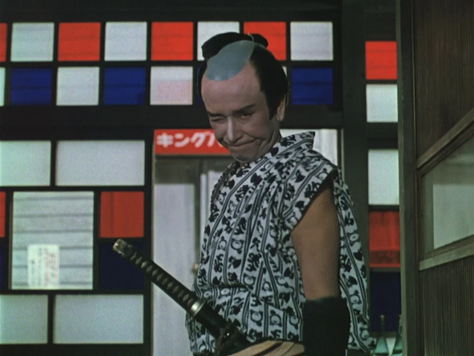 Floating Weeds (1959) movie still: medium — An interior space features sliding screens with red, white, and blue grid panels. A man in a patterned…