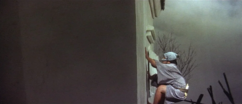 An Actor’s Revenge (1963) movie still: wide — A stark white stone wall rises into a dark, overcast night sky. A man dressed in a patterned kimono…
