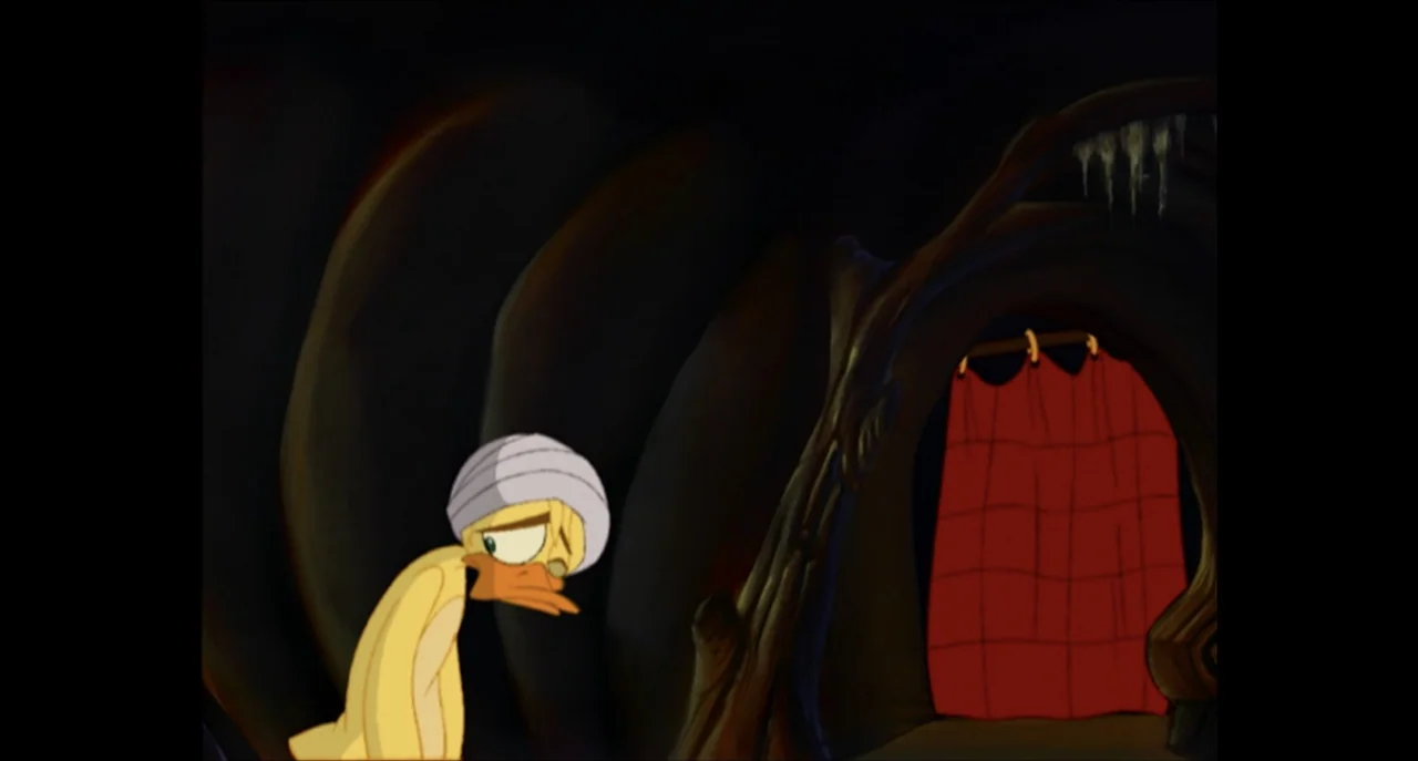 The Sissy Duckling (1999) movie still: medium — A dark cave interior features smooth, curved walls and a red curtained arched doorway. A yellow…