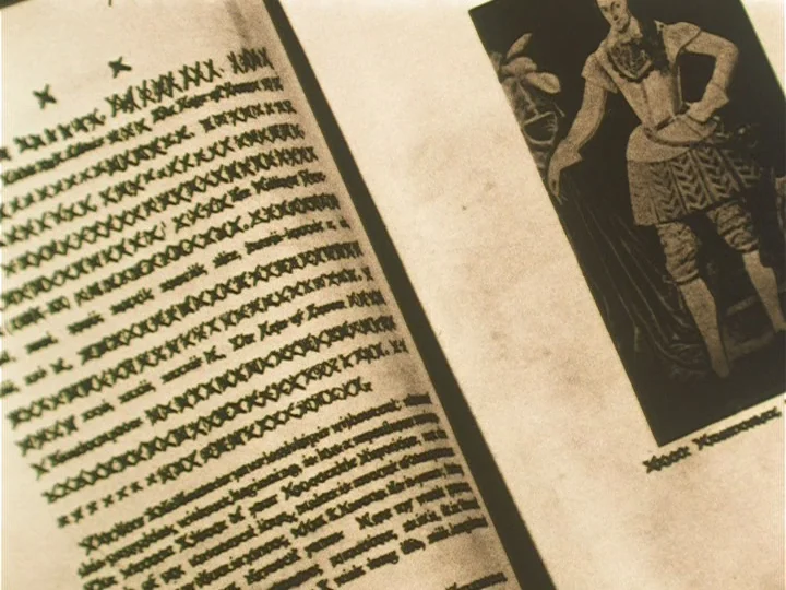 The Reading Machine (1977) movie still: closeup — An open antique book displays black printed text alongside a printed historical portrait. The aged…