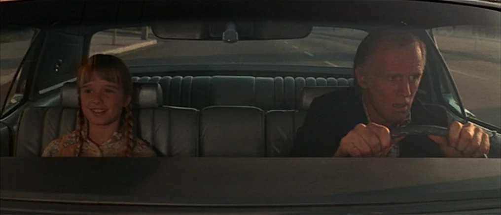 Assault on Precinct 13 (1976) movie still: medium — A 1970s car interior with leather upholstery and a rear-view mirror. An older man sits at the…