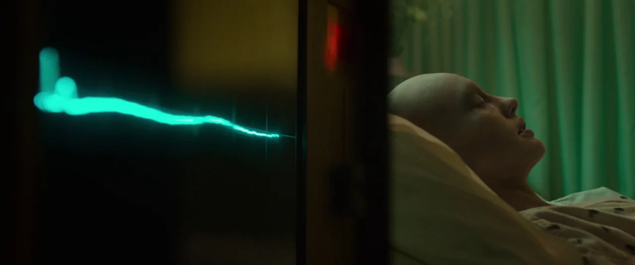 Guardians of the Galaxy (2014) movie still: medium — A hospital room is bathed in the green glow of a medical monitor. A young woman with a shaved…
