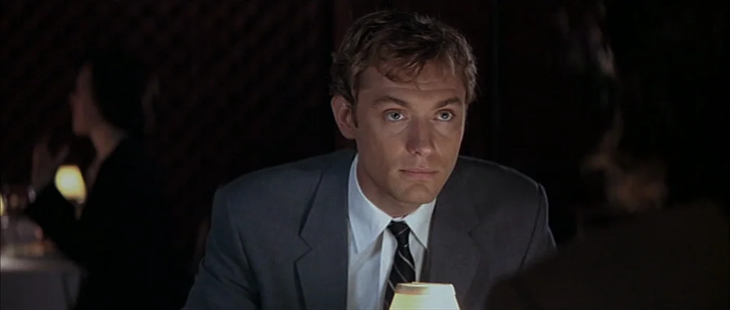 I Heart Huckabees (2004) movie still: medium — A dimly lit dining area features dark, indistinct backgrounds and a close table setting. A man in a…