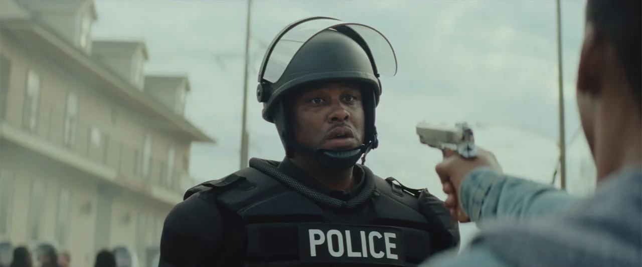 Queen & Slim (2019) movie still: medium — A residential street with multi-story apartment buildings provides a background to a tense confrontation.…