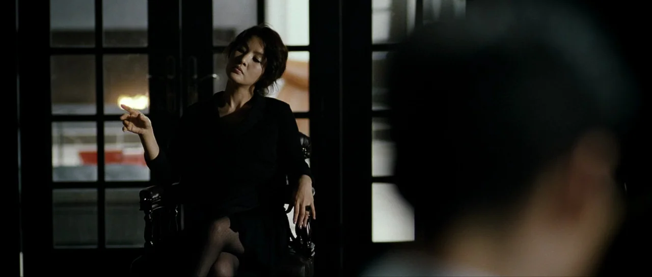 The Housemaid (2010) (2010) movie still: medium — A dark, modern office space features glass-paned doors that reveal faint exterior city light. A…