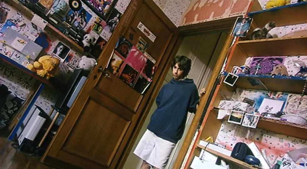 Scarlet Diva (2000) movie still: fullbody — A cluttered teenager's room features walls covered in posters, photographs, and various personal…