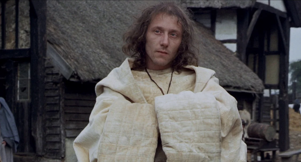 The Canterbury Tales (1972) movie still: medium — An outdoor village setting features dark timber-framed houses with thatched roofs in the…