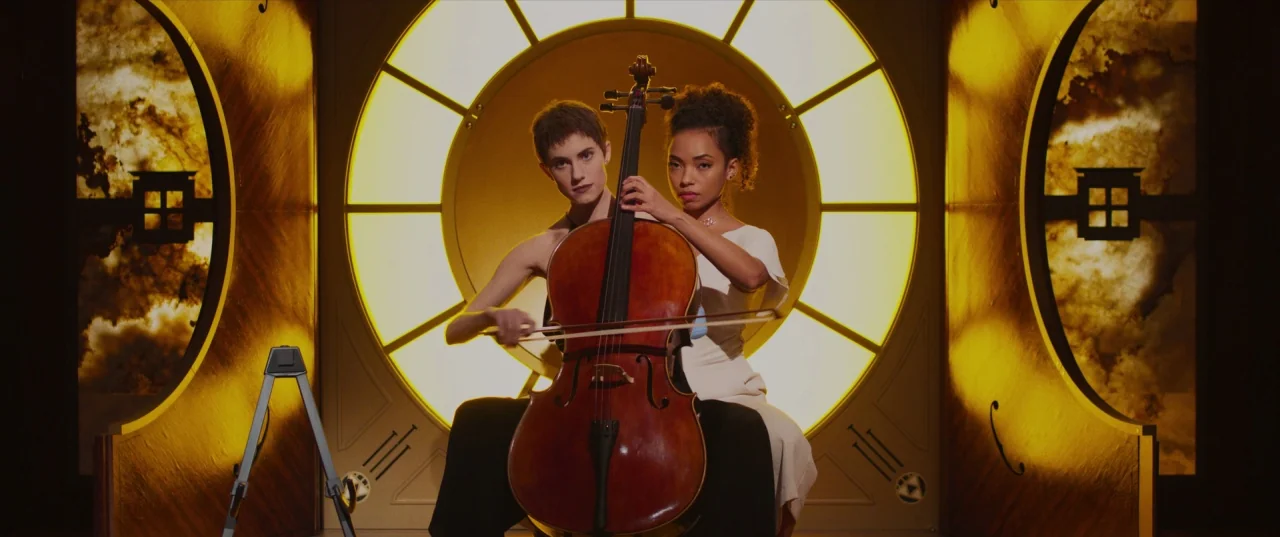 The Perfection (2018) movie still: medium — Two women play a cello centered before a large glowing circular architectural structure. The background…