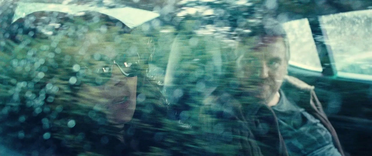 Clouds of Sils Maria (2014) movie still: medium — The interior of a car features two people viewed through a rain-slicked window. Raindrops blur the…