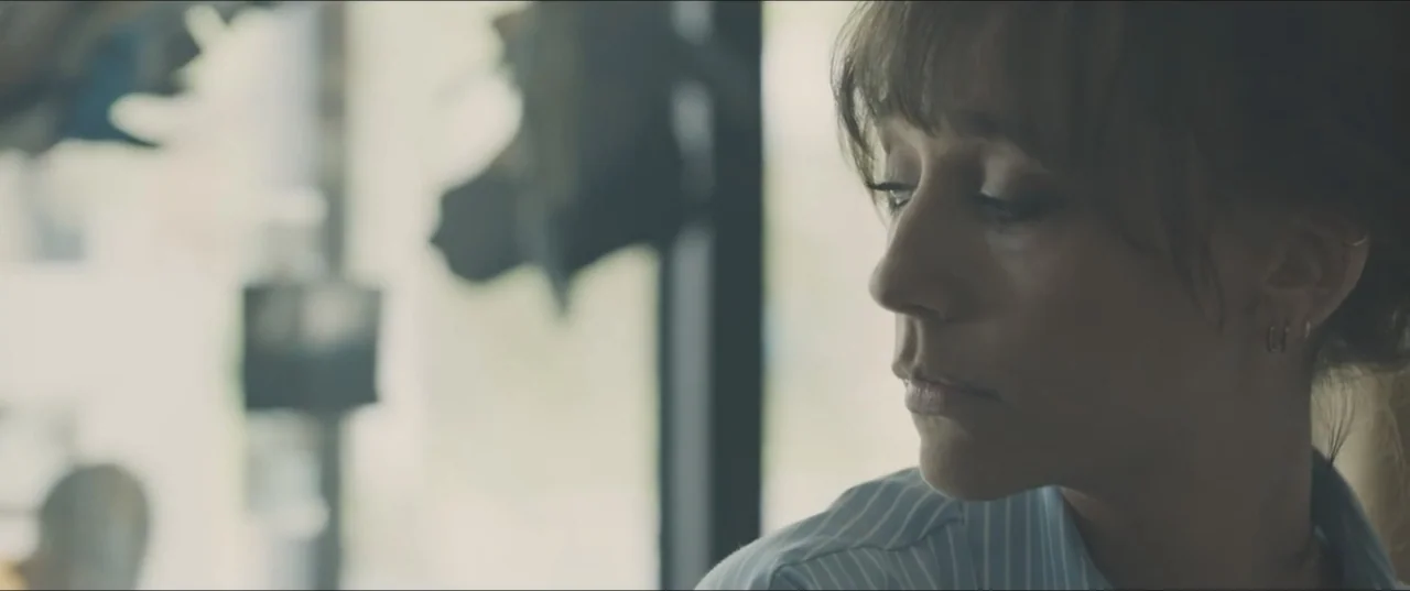 Zoe (2018) movie still: closeup — A quiet indoor setting with a large window in the background.
