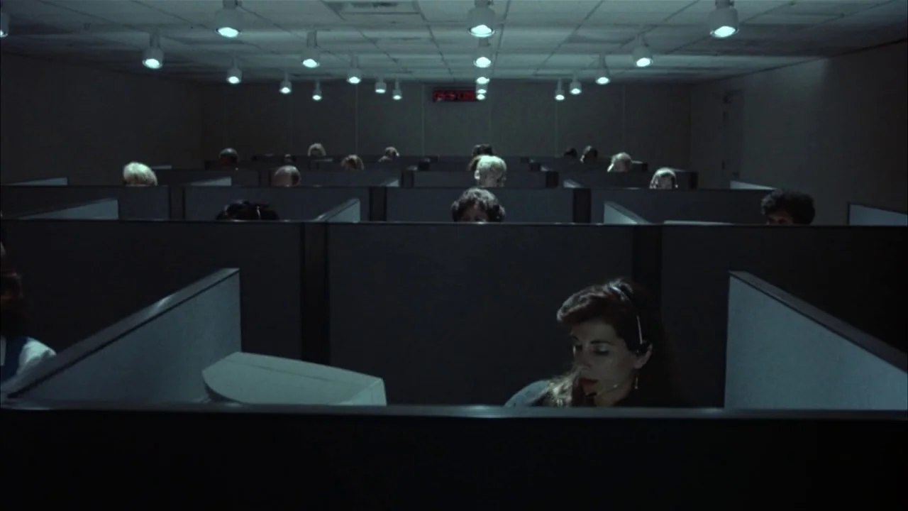 The Rapture (1991) movie still: wide — A dense grid of grey cubicles fills an office space with recessed ceiling lights. Multiple employees sit at…