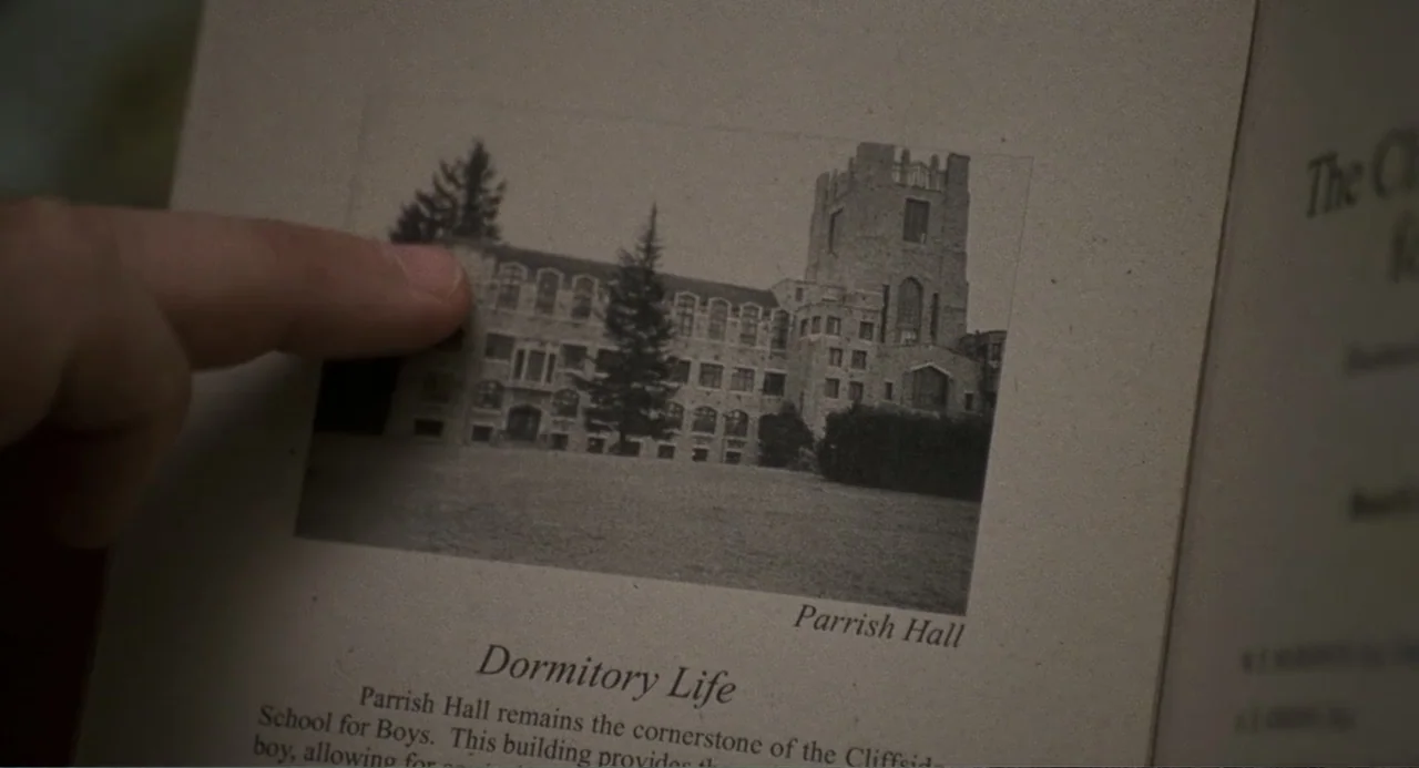 Jumanji (1995) movie still: closeup — An open textbook page features a black and white photograph of an old stone building labeled Parrish Hall. A…