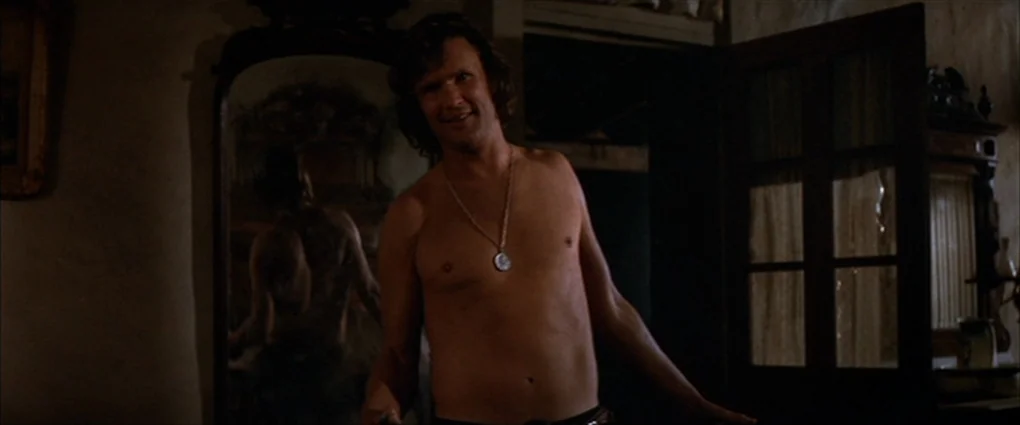 Pat Garrett & Billy The Kid (1973) movie still: medium — A dark indoor setting features a vintage mirror reflecting the subject's back. A…
