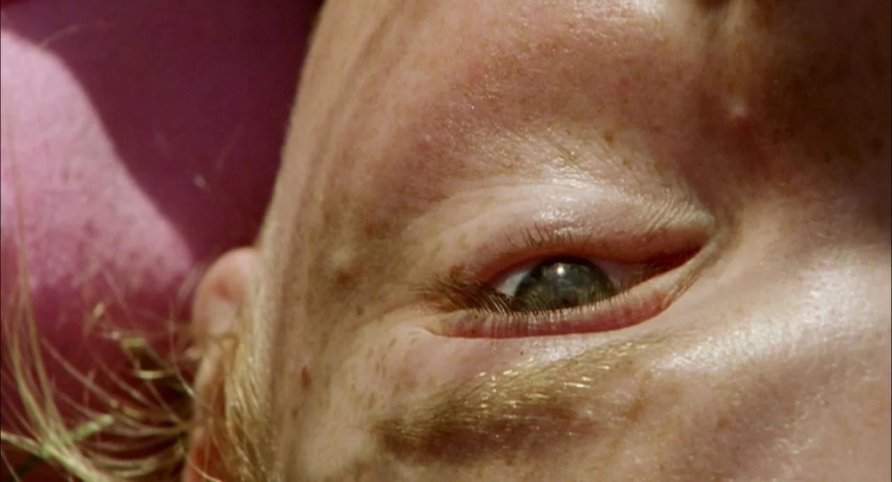My Summer of Love movie still: closeup — Close-up view of a young person's face against a pink surface outdoors. The subject's eye is open and…