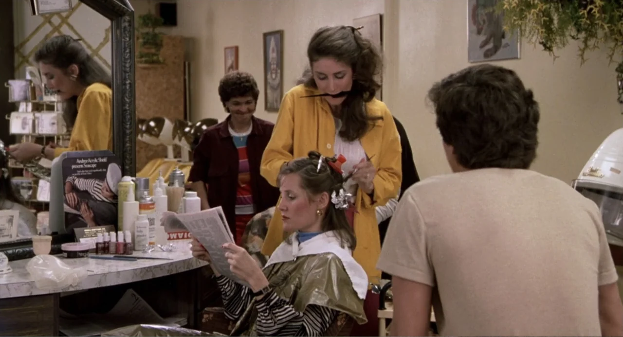 Harry and the Butler (1961) movie still: medium — A bustling 1980s hair salon features styling stations with mirrors and various hair products. A…