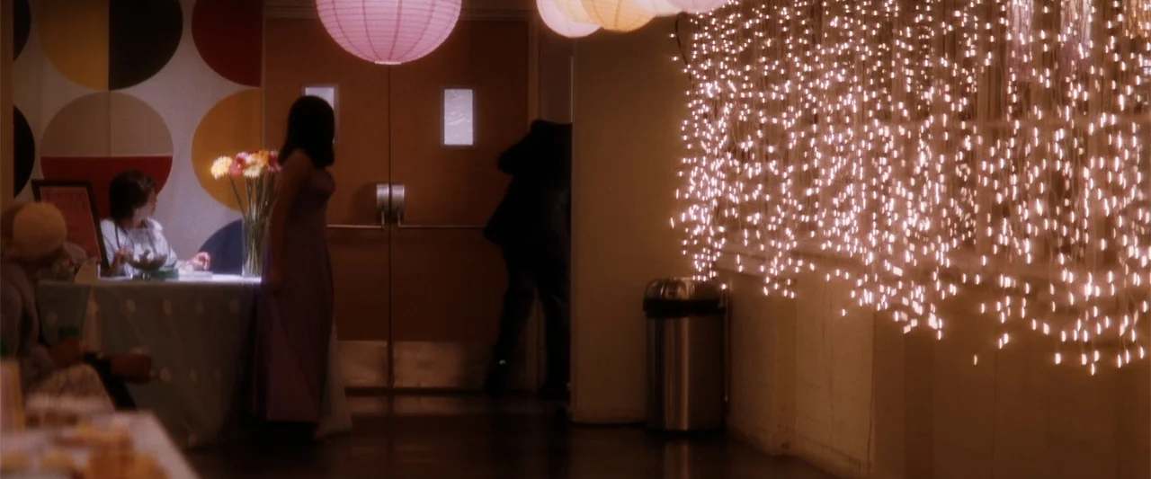 My Sister's Keeper (2023) movie still: wide — A decorated interior space with paper lanterns and strings of lights along the wall. A person in a…