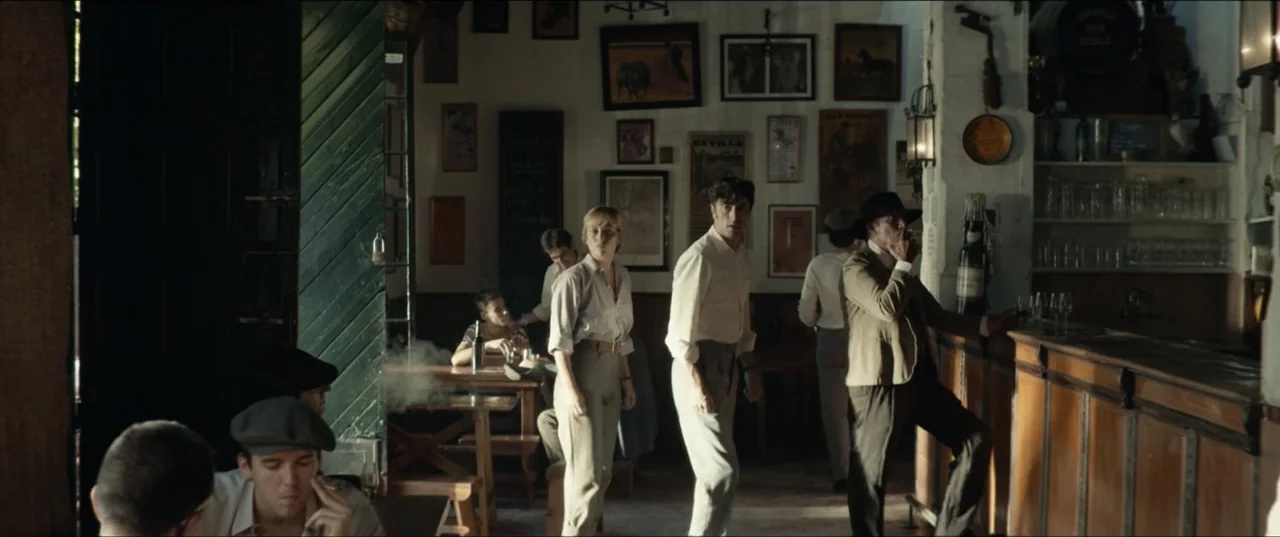 Hear Me: Our Summer (2024) movie still: wide — A dimly lit 1940s tavern with wooden furniture and framed posters on the walls. A small group of…