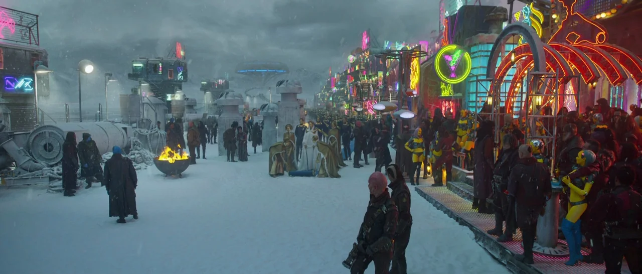 Guardians of the Galaxy Vol. 2 (2017) movie still: wide — A snowy futuristic plaza is lined with vibrant neon signs under a dark sky. A large crowd…