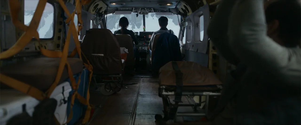 Flight Risk (2025) movie still: medium — The interior of a small utility aircraft contains pilots and cargo. Two figures sit in the cockpit seats…