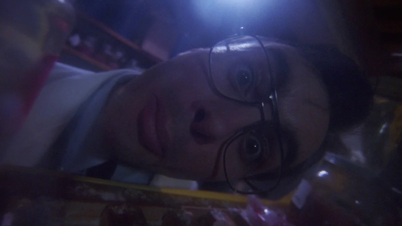 Bride of Reanimator (1989) movie still: closeup — A man peers into the illuminated interior of a dark kitchen appliance. The high-angle perspective…