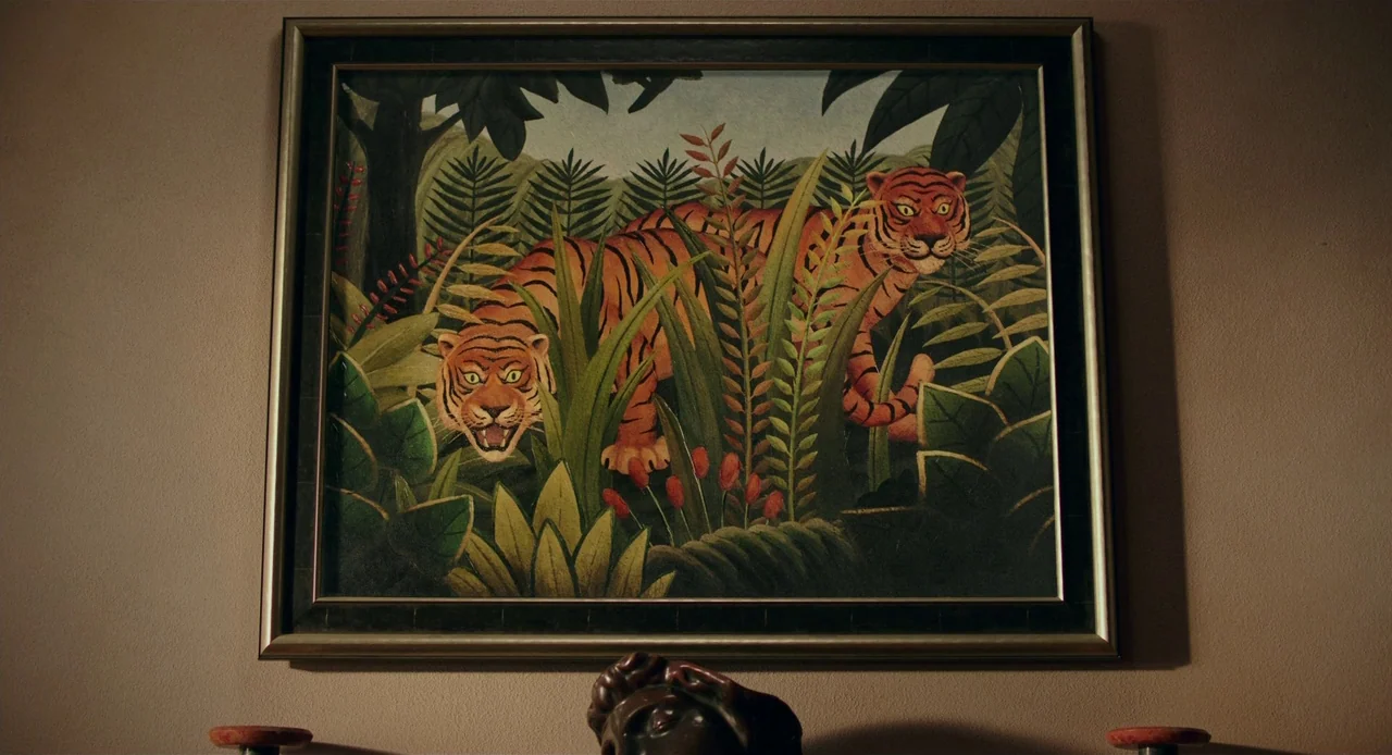 Jojo Rabbit (2019) movie still: closeup — A framed reproduction of Henri Rousseau's tiger painting hangs on a beige wall. A small bust is partially…