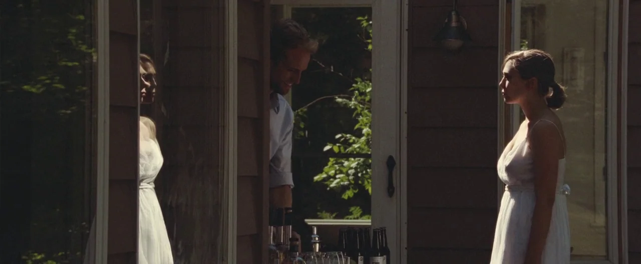 Martha Marcy May Marlene (2011) movie still: medium — A wooden house exterior features large glass doors and vertical siding with outdoor lighting.…