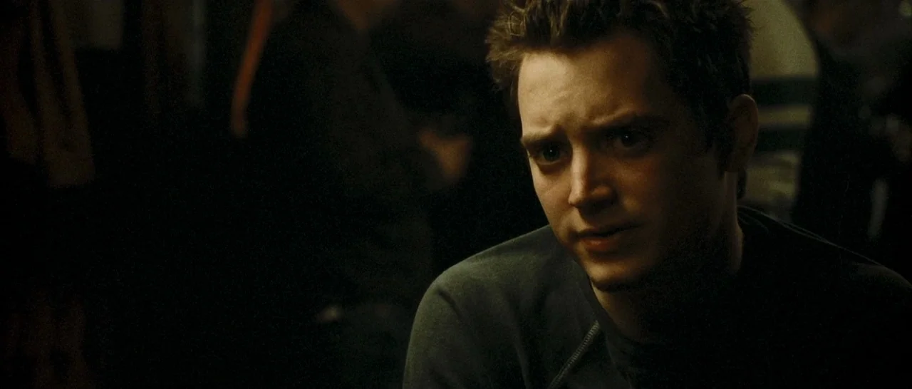 Green Street (2005) movie still: closeup — A dimly lit bar setting with dark, indistinct shapes in the background. A young man sits in the…
