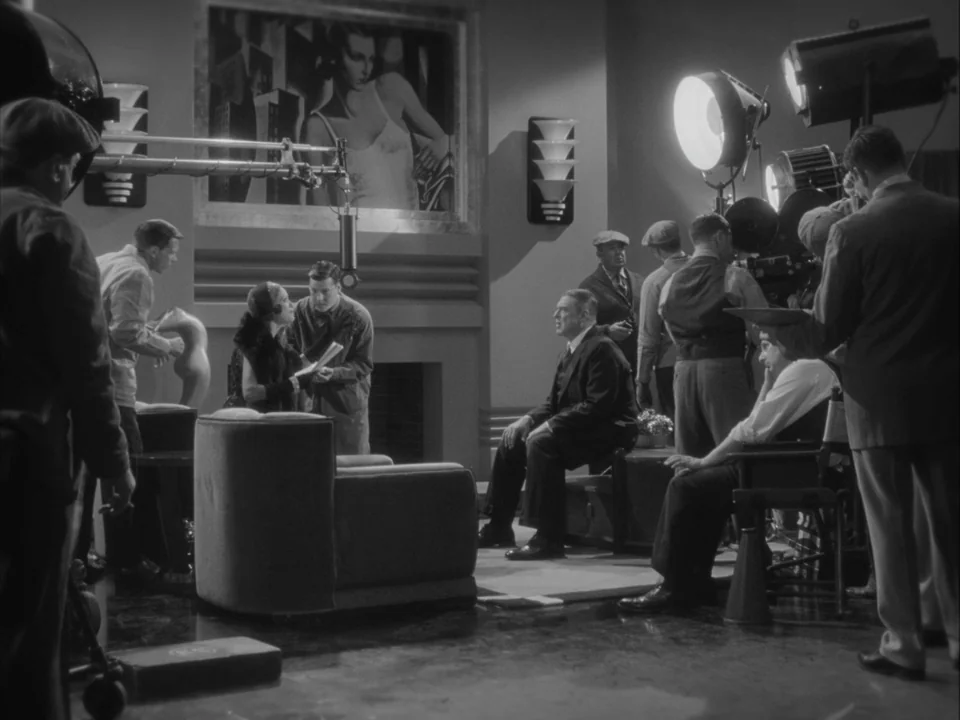 The Artist (2011) movie still: wide — A film production set featuring studio lights, a camera crane, and decorative wall art. Actors and crew…