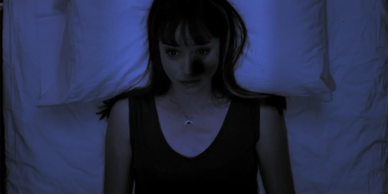 Stalked by My Doctor: A Sleepwalker's Nightmare (2019) movie still: closeup — A dimly lit interior space with a person lying on white bedding. A…