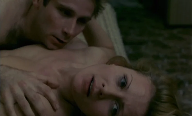 No End (1985) movie still: closeup — A dimly lit room provides a background for two individuals lying on a surface. A man hovers closely over a…
