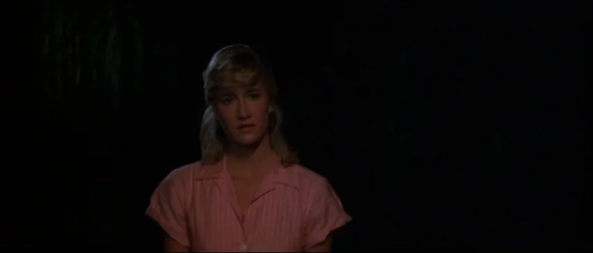 Blue Velvet (1986) movie still: medium — A woman stands centered against a deep black void with no visible environmental details. The subject is…
