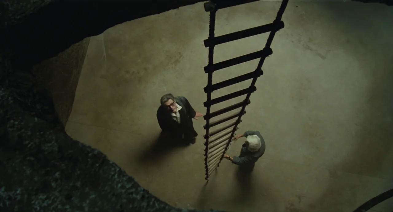 City of Women (1980) movie still: wide — A stark concrete room features a dark circular opening in the ceiling above. Two men stand on the smooth…