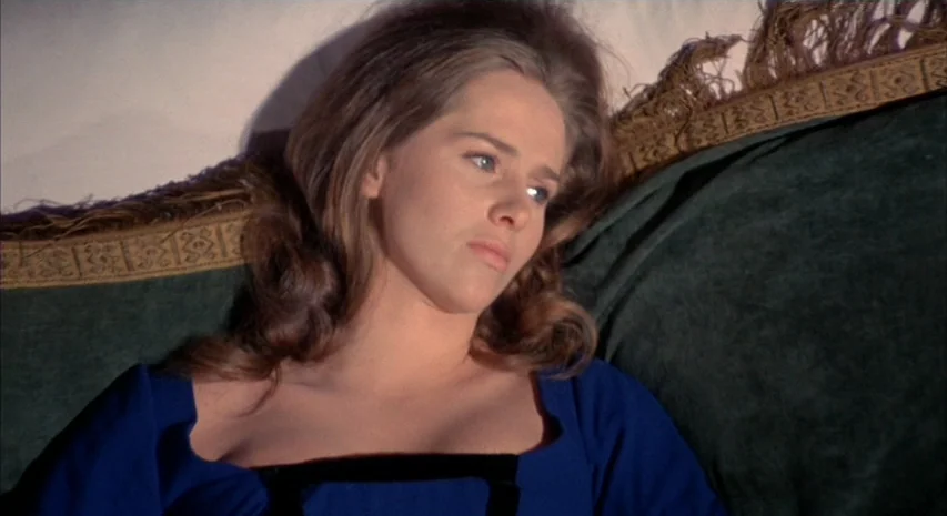 Witchfinder General (1968) movie still: closeup — A person rests upon a dark green couch featuring a fringed gold edge detail. The subject is…