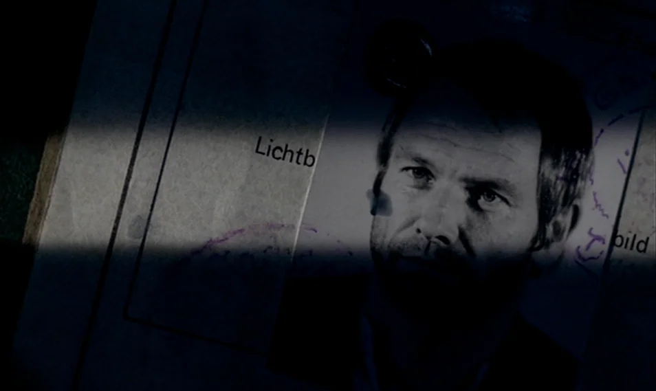 Despair (1978) movie still: closeup — An official identification card features a printed black and white portrait of a man. A band of light masks…