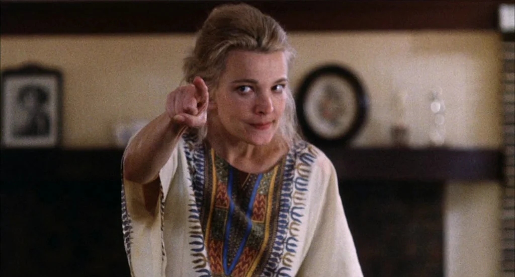 A Woman Under the Influence (1974) movie still: medium — A residential living room features a fireplace mantle with circular wall decor. A woman in…