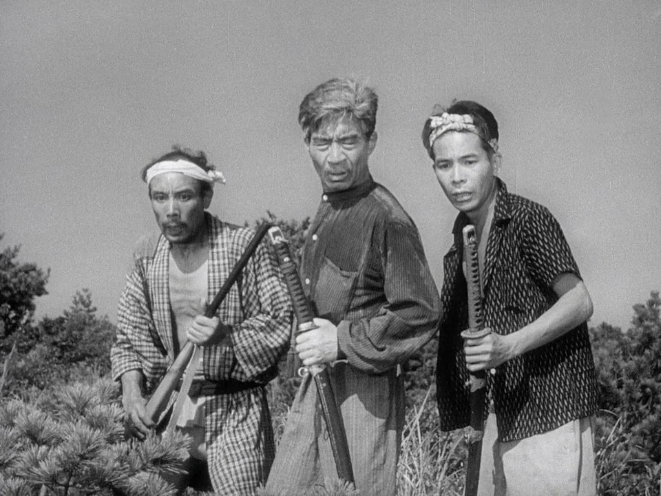 Godzilla (1954) (1954) movie still: medium — Three Japanese men stand in an open field with sparse vegetation in the background. They hold katana…